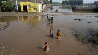 People wade through floodwaters, in Charsadda, Pakistan