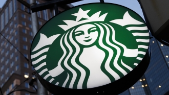 A Starbucks sign hangs outside a Starbucks coffee shop.