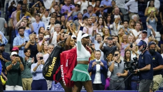 Sisters Serena and Venus Williams wave at the crowd as they head off the tennis court
