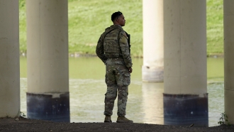 A member of the Texas National Guard looks across the Rio Grande to Mexico from the U.S. at Eagle Pass, Texas.