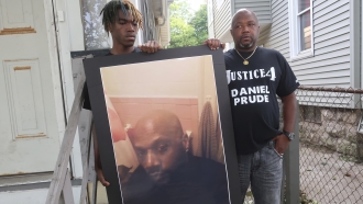 Joe Prude, brother of Daniel Prude, right, and his son Armin, stand with a picture of Daniel Prude in Rochester