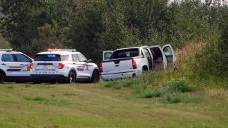 Police and investigators are seen at the side of the road outside Rosthern, Saskatchewan