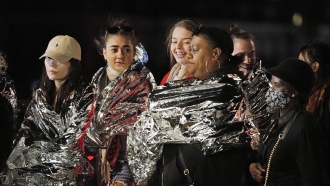 People in warming foil wait to see the late Queen Elizabeth II.