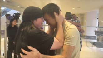 Andy Huynh, left, and Alex Drueke, far right, are seen hugging their loved ones after arriving.