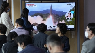 People watch a news program showing a file image of a missile launch by North Korea