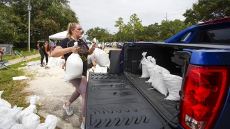A woman loads sandbags into her truck in preparation for a hurricane