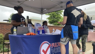 People visit a booth set up by Fulton County in Georgia to recruit new poll workers.