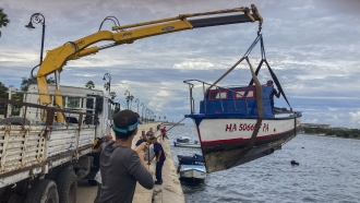 Workers remove a boat from the water in the bay of Havana, Cuba