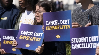 Activists hold signs during a news conference on student debt cancellation on Capitol Hill in Washington