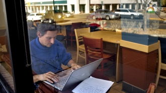 Man working on a laptop at a coffee shop.