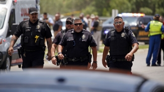 Police walk near Robb Elementary School following a shooting, May 24, 2022, in Uvalde, Texas.