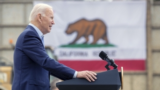 President Joe Biden speaks in front of a California state flag.