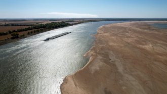 A barge maneuvers its way down the normally wide Mississippi River where it has been reduced to a narrow trickle