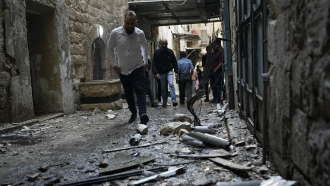 Palestinians walk through the site of an Israeli attack.