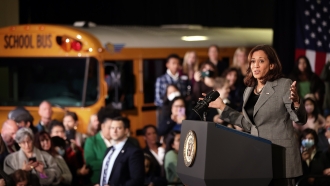 Vice President Kamala Harris speaks in front of a crowd and a school bus