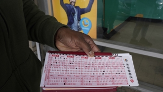 Carol Davis displays her Powerball picks as she waits in line to purchase tickets at Lichine's Liquor & Deli in Sacramento