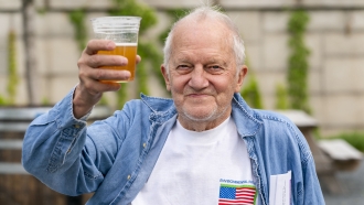George Ripley, 72, of Washington, holds up his free beer after receiving the J & J COVID-19 vaccine shot