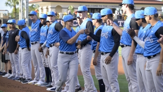 A baseball manager exchanges fist bumps with players.