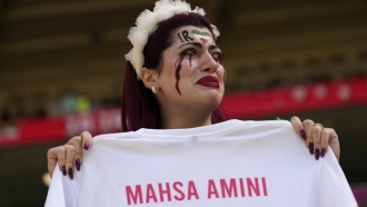 Iranian soccer fan holds a 'Mahsa Amini' shirt.