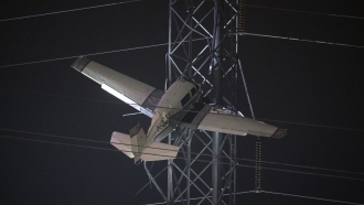 A small plane rests on live power lines after crashing