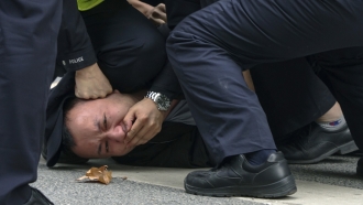 Police officers pin down and arrest a protester on a street in Shanghai, China.