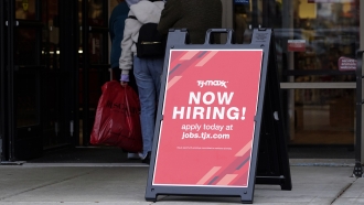 Hiring sign is displayed outside of a retail store.