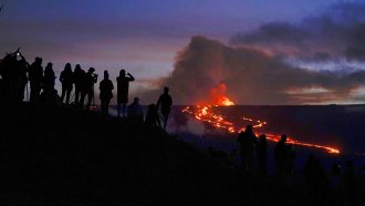 People watch and record images of lava from the Mauna Loa volcano