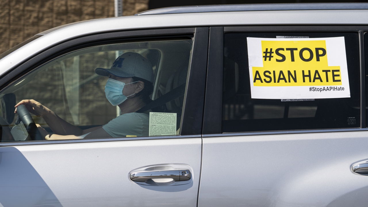 A sign reading: "#Stop Asian Hate" is displayed in a vehicle window