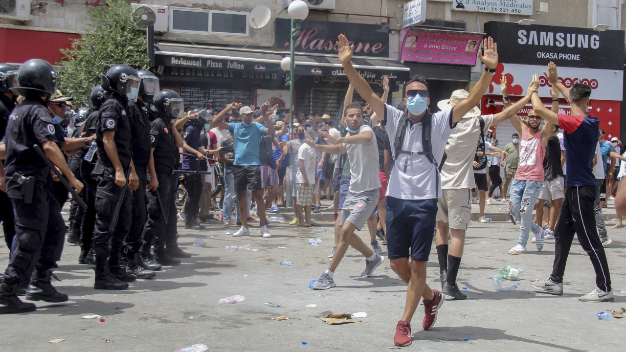 Protesters face Tunisian police officers during a demonstration in Tunis, Tunisia, Sunday, July 25, 2021.