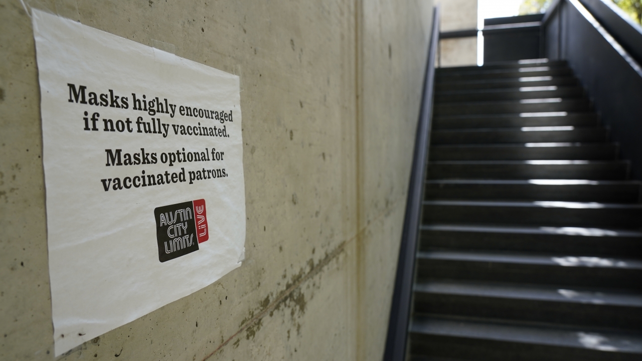 A sign requesting masks be worn is displayed near the entrance to the Moody Theater in Austin, Texas.