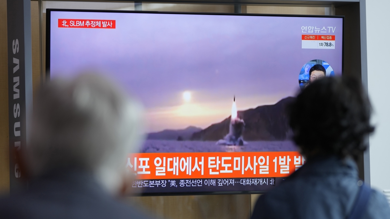 People watch a TV screen showing a news program reporting about North Korea's missile launch.