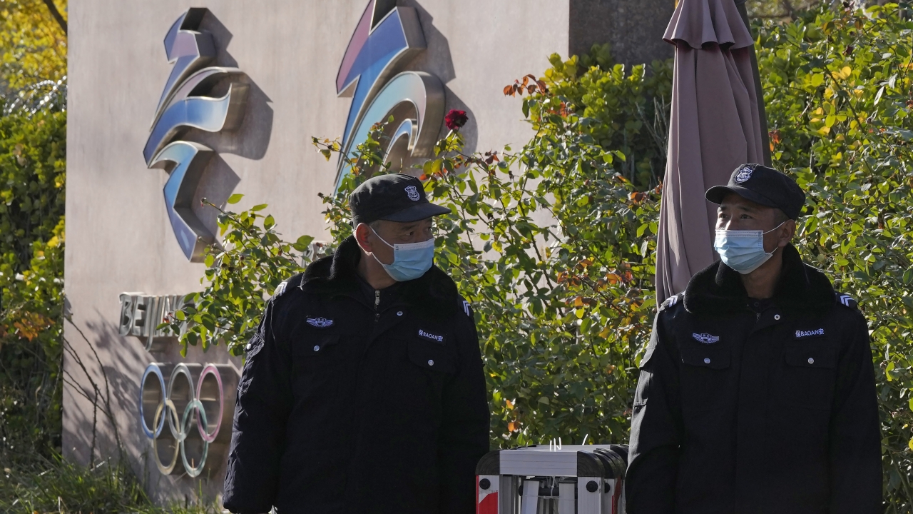 Security guards patrol near the logos for the Beijing Winter Olympics and Paralympics