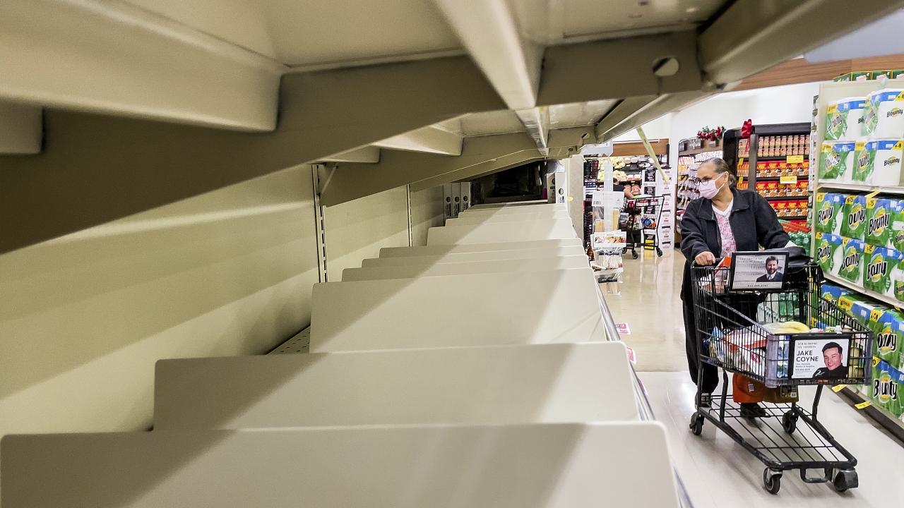 A shopper passes empty shelves