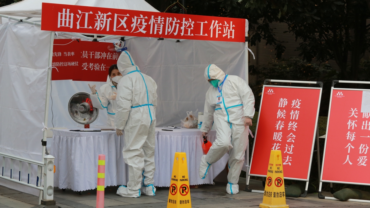 Government workers in protective clothing gather at a work station for pandemic control outside a residential block in Xi'an.