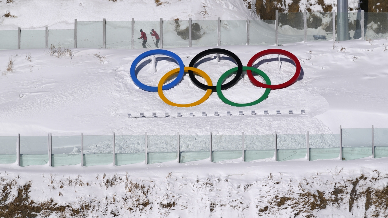 Biathletes skate above the Olympic rings during practice at the 2022 Winter Olympics