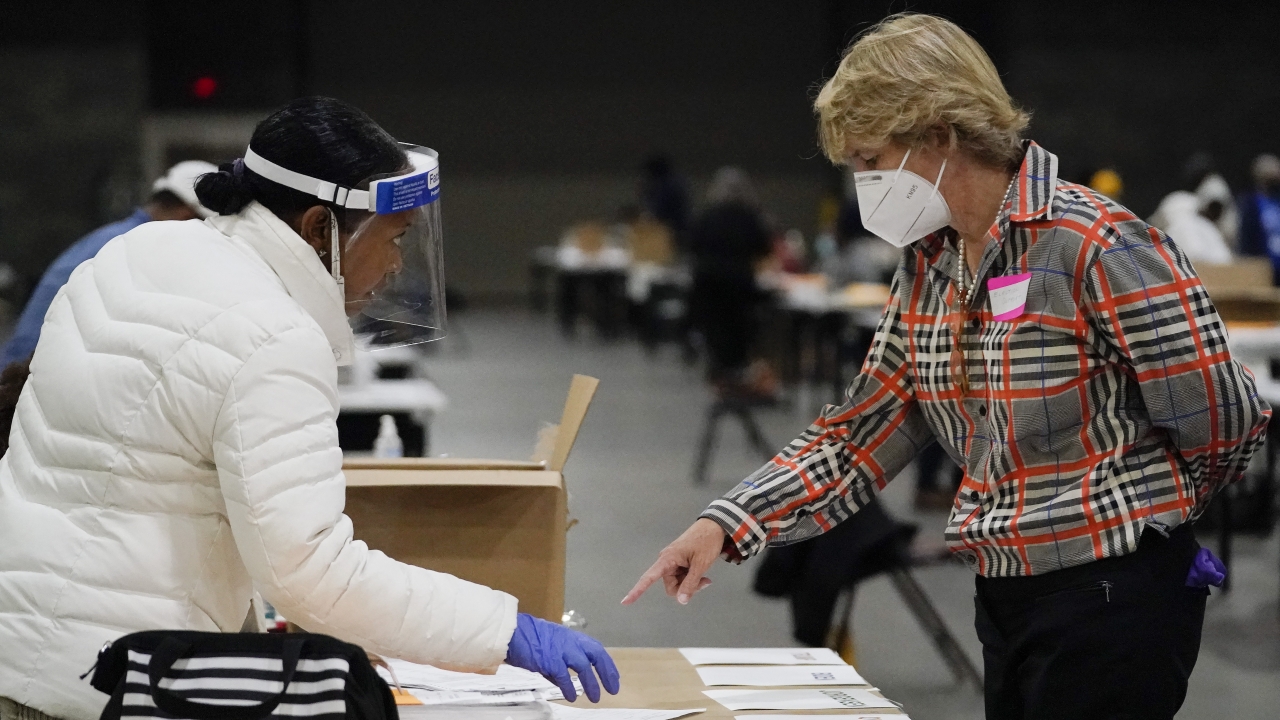 An election official helps another as they sort ballots during an audit