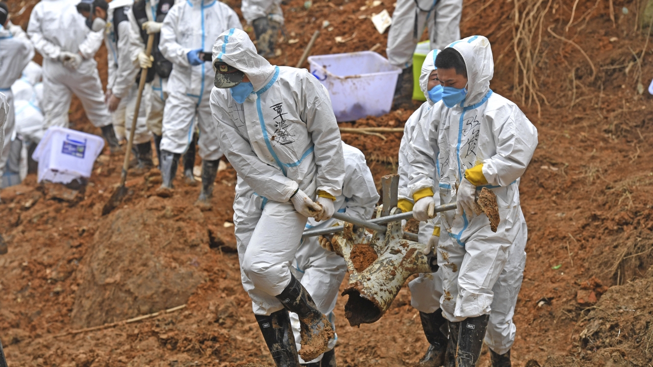 In this photo released by Xinhua News Agency, rescuers carry a piece of plane wreckage.