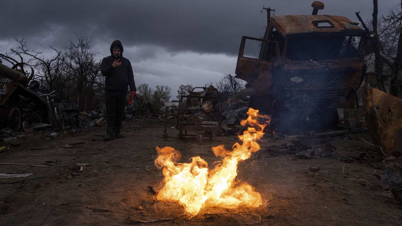 A man takes a photo of burning propellant in a street near destroyed Russian military vehicles near Chernihiv, Ukraine
