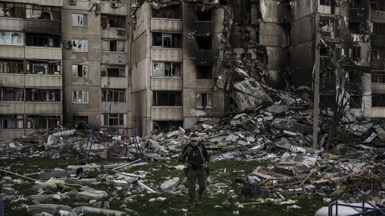 A Ukrainian serviceman walks amid the rubble of a building heavily damaged by multiple Russian bombardments