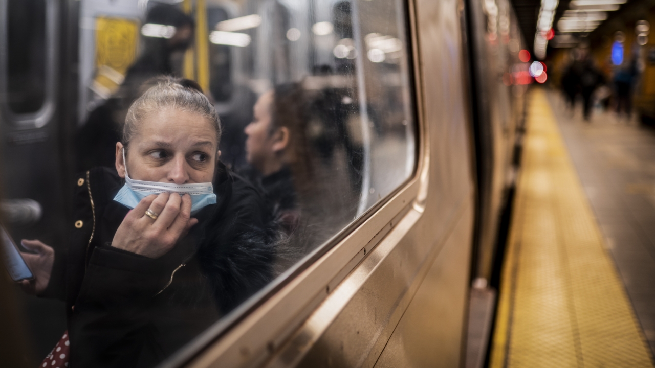 A passenger looks out the window onto the platform while riding a subway train