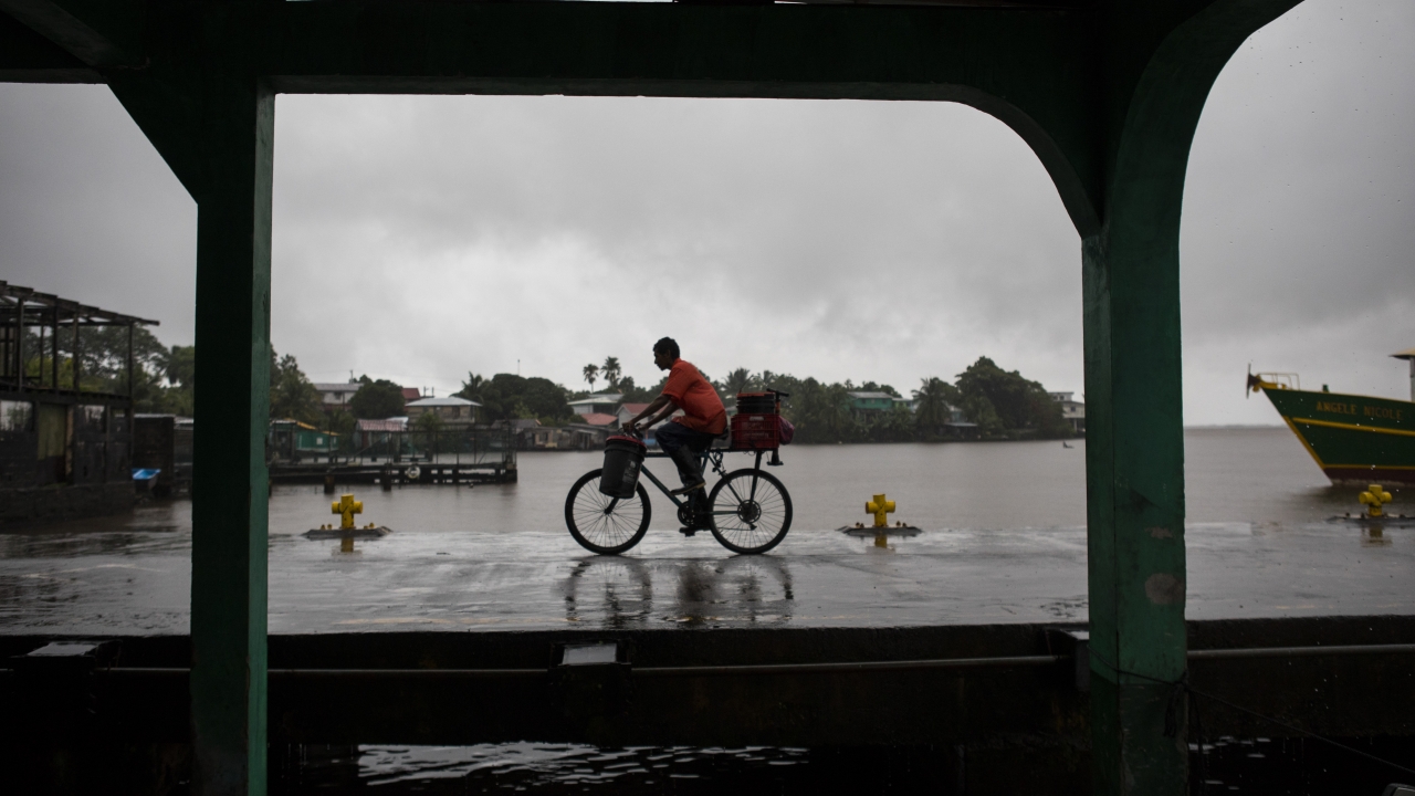 Man riding bike through rain brought by tropical storm