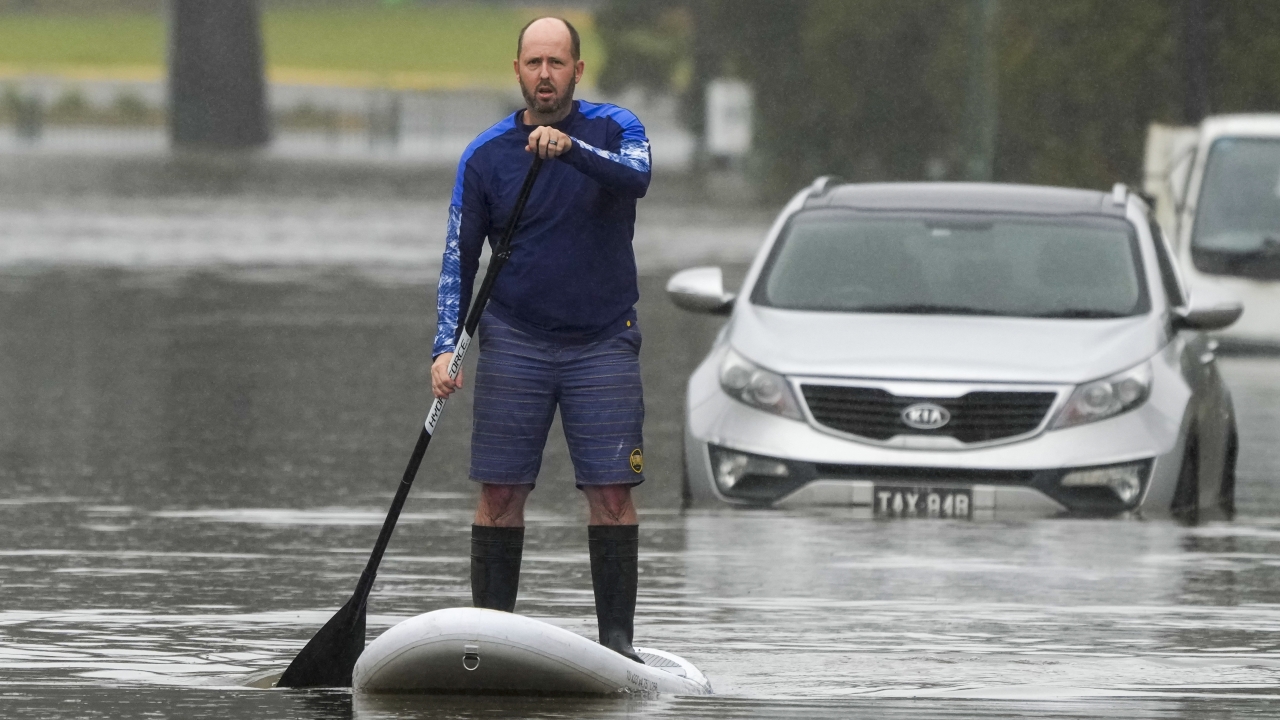 Man paddle boards down flooded street