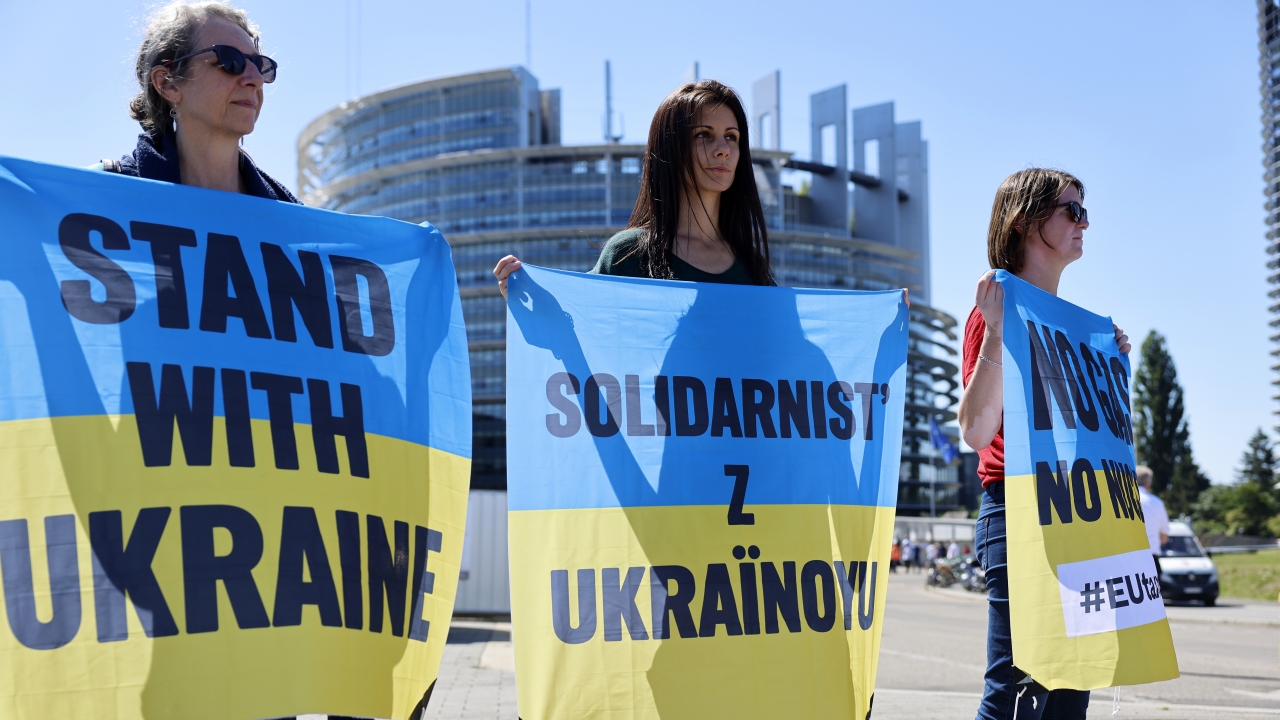 Climate activists hold banners that say "Stand With Ukraine."