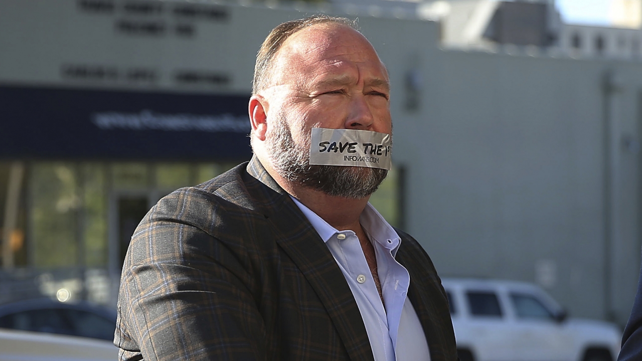 Alex Jones with tape over his mouth reading "save the 1st."