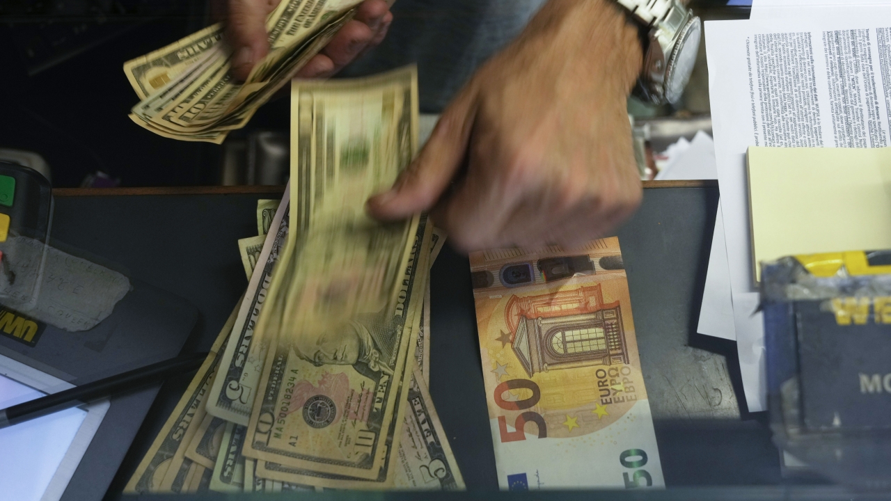 Cashier changes Euro banknote with U.S. dollars