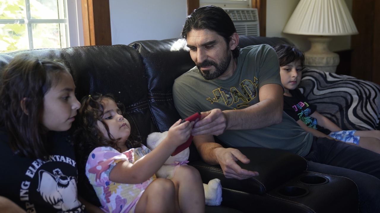 A man who fled Afghanistan with his family sits with three of his children.
