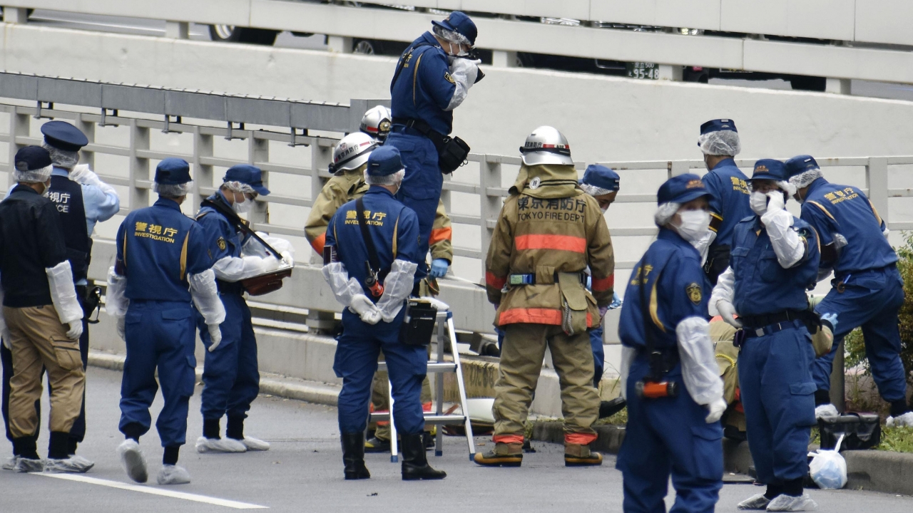 Police and firefighters in Tokyo inspect the scene where a man is reported to set himself on fire