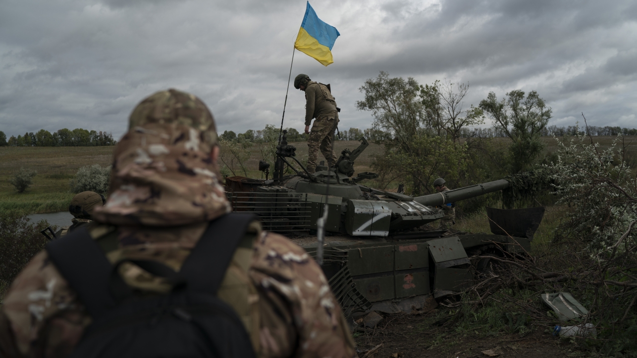 A Ukrainian national guard serviceman stands atop a destroyed Russian tank.