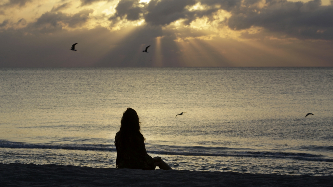 A woman meditates on a beach