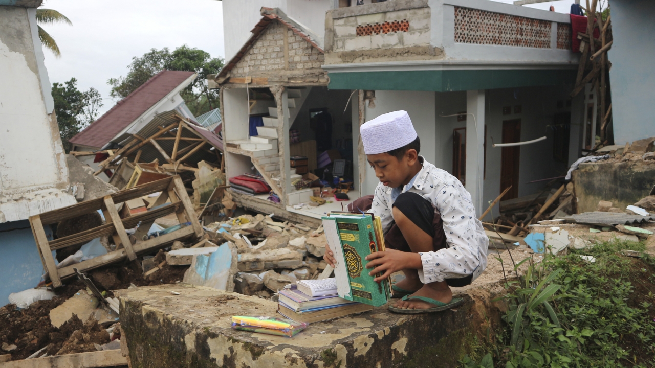 Boy collects books from the rubble following an earthquake in Indonesia.